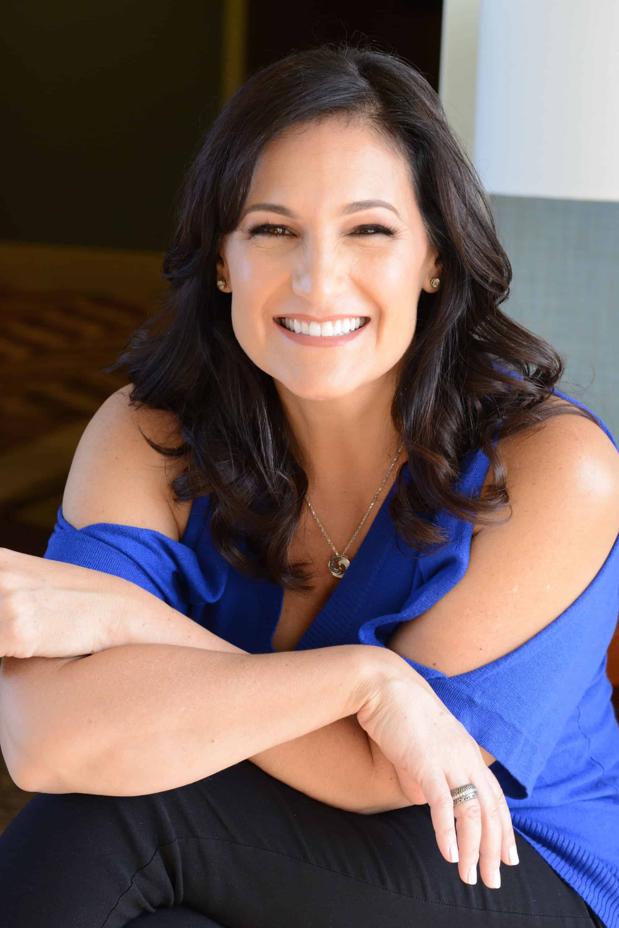 Spiritual Healer Christy Whitman Smiling and Crossing Her Arms in a Blue Blouse